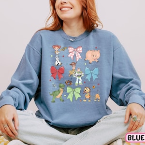 a woman sitting on a bed wearing a blue sweatshirt