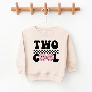 a sweater hanging on a clothes rack with two cool faces on it
