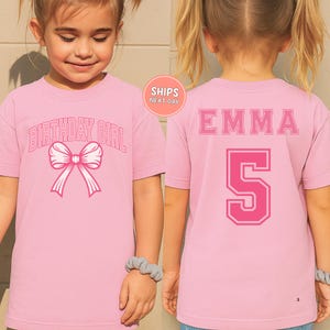 A young girl wearing a pink t-shirt with the text "BIRTHDAY GIRL" and a pink bow on the front.