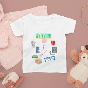 Brinquedos favoritos como cabelo de mãe, carregador de telefone, copo, vassoura, óculos, controle remoto de TV, caixa de papelão, garrafa de água, controle remoto de TV, tigela de cachorro, camiseta de bebê