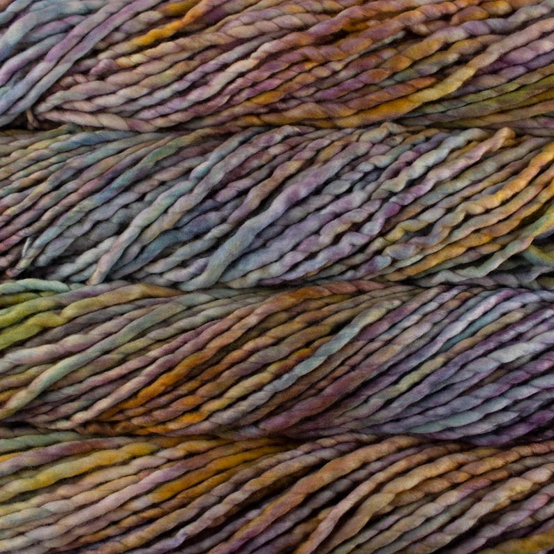 May include: Close-up of thick, hand-dyed yarn in shades of purple, gold, and blue. The yarn has a textured, chunky appearance, ideal for knitting or crocheting projects. The color variations create a visually appealing, artistic effect.