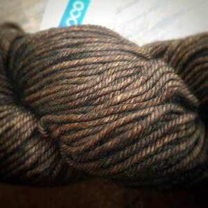 Malabrigo Rios Coco Tonal Espresso Superwash Merino Yarn, a brown and black skein of yarn with subtle color variations, showcasing its rich texture and earthy tones, from the popular brand Malabrigo.