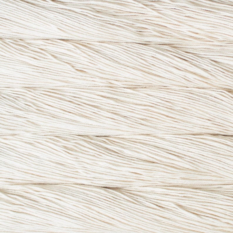 Puede incluir: Una vista de cerca de m&uacute;ltiples hebras de hilo de color blanco roto dispuestas en l&iacute;neas horizontales paralelas. La textura de las fibras retorcidas es claramente visible, mostrando los cabos individuales del hilo mientras recorren el marco.