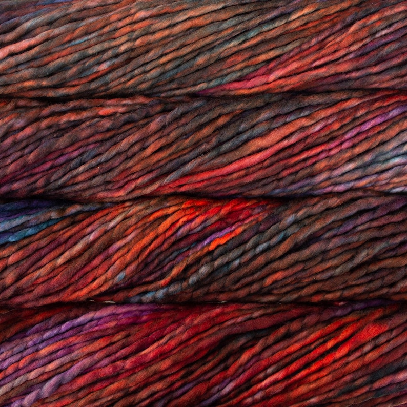 May include: Close-up of a skein of hand-dyed yarn in shades of red, orange, brown, and purple. The yarn has a thick, textured appearance, with visible strands and color variations. Ideal for knitting and crochet projects.