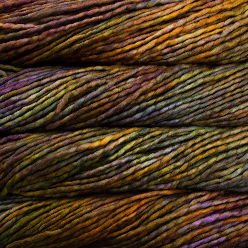 May include: Close-up of a skein of hand-dyed yarn in shades of brown, orange, purple, and green. The yarn has a thick, textured appearance, ideal for knitting or crocheting projects. The colors blend together, creating a rich, earthy look.