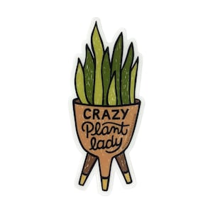 May include: A sticker featuring a stylized illustration of a potted plant with the text "Crazy Plant Lady." The plant has green and yellow leaves, and the pot is brown with three legs. The text is in a handwritten style.