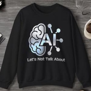 Peut inclure: Un sweat-shirt noir à manches longues arborant un graphique représentant un cerveau stylisé relié à un réseau de nœuds à côté des lettres AI. Sous le graphique, le texte Let's Not Talk About est écrit dans une police blanche sans empattement.