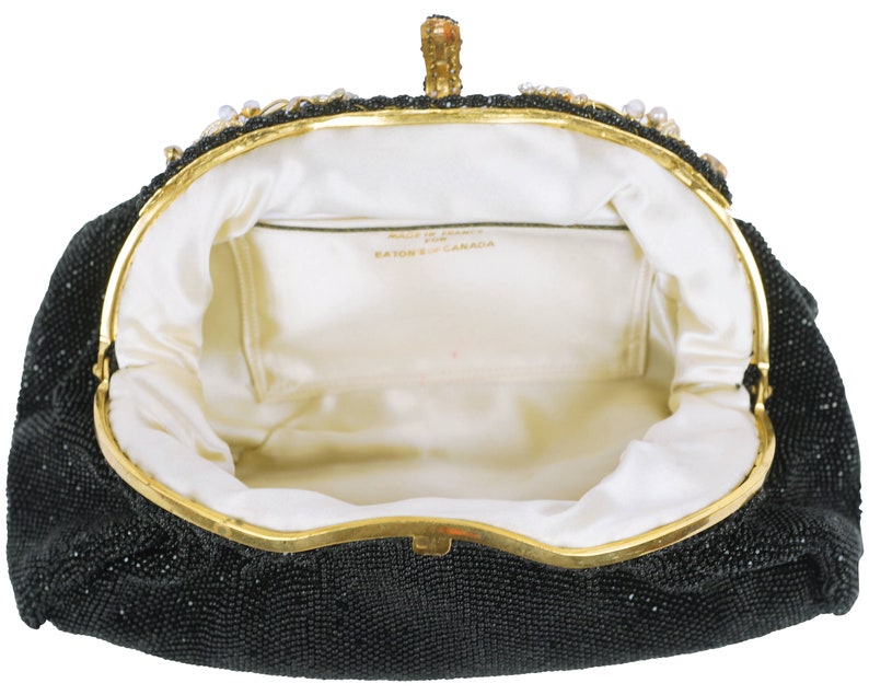 May include: Black beaded evening bag with a gold clasp and a white satin lining. The bag has a label that reads "Made in Canada, Eaton's".