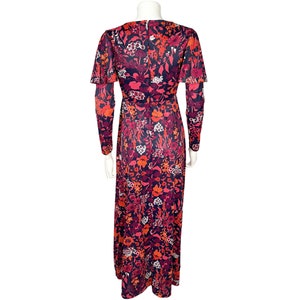 May include: A floor-length dress featuring a vibrant floral pattern in shades of dark blue, bright red, orange, and white. The garment has long sleeves with flared cuffs, a fitted waist, and a concealed zipper closure along the center back.