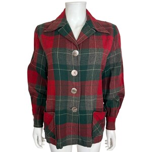 May include: A red, green, and grey plaid jacket with three large, silver-coloured buttons. The jacket has a collared neckline, two front pockets, and long sleeves. The jacket is displayed on a white mannequin.