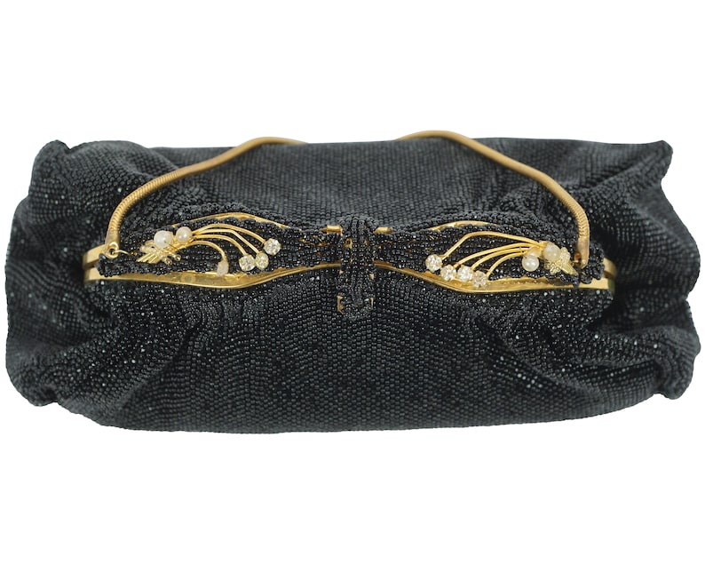 May include: A black beaded evening bag with a gold clasp and a decorative floral design. The clasp features small white stones.