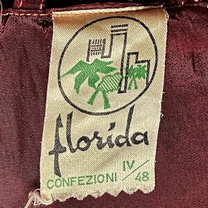 May include: A white tag with a black and green logo of a palm tree and a building. The text "Florida Confezioni IV/48" is printed on the tag.