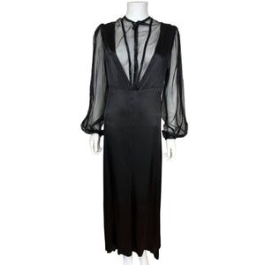Puede incluir: Un vestido negro vintage con una parte superior transparente de manga larga y un cuello alto. El corpiño presenta un diseño abotonado y el vestido tiene una falda larga y fluida. El vestido se exhibe en un maniquí.