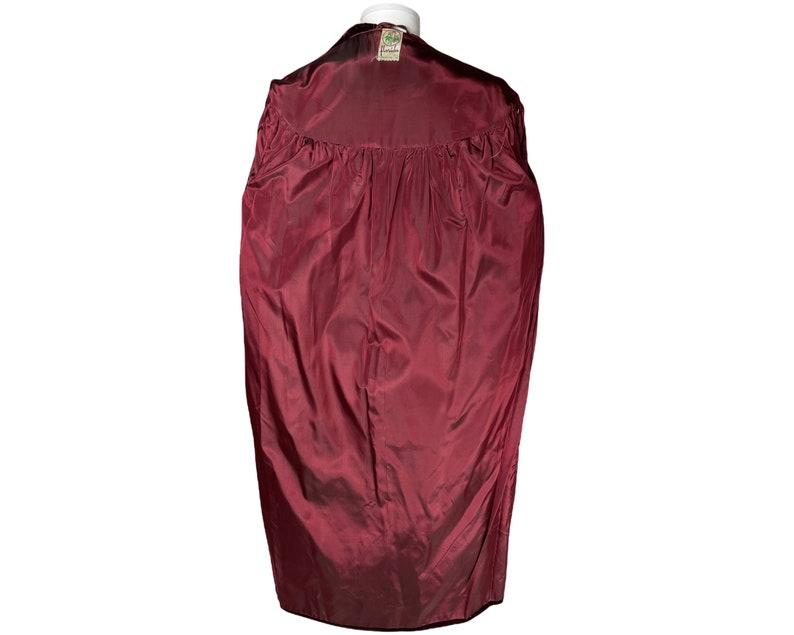 May include: A burgundy velvet jacket with a green label on the back.