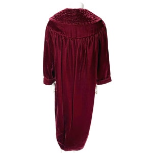 May include: A long, burgundy velvet robe with a large, quilted collar. The robe has long sleeves and a gathered waist.
