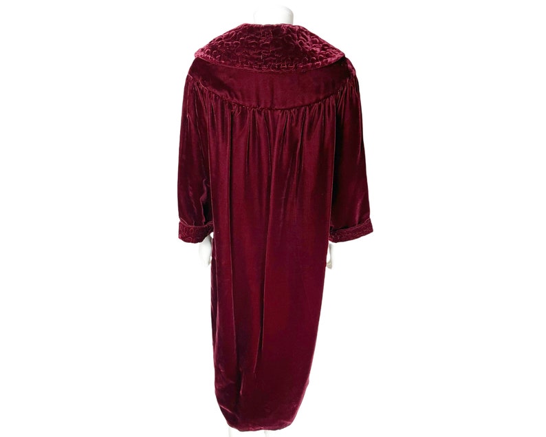 May include: A long, burgundy velvet robe with a large, quilted collar. The robe has long sleeves and a gathered waist.
