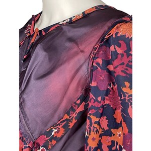 May include: A garment featuring a dark purple solid fabric panel alongside a patterned section with a floral design in shades of red, orange, and dark blue. The piece includes a round neckline and a visible seam connecting the two distinct fabric types.