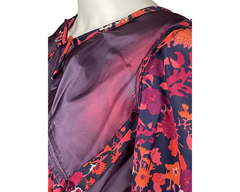 May include: A garment featuring a dark purple solid fabric panel alongside a patterned section with a floral design in shades of red, orange, and dark blue. The piece includes a round neckline and a visible seam connecting the two distinct fabric types.