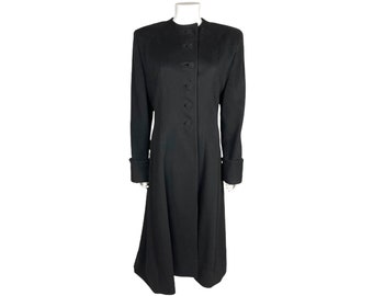 Può includere: Un cappotto lungo nero con colletto alla coreana e chiusura a bottoni. Il cappotto presenta maniche lunghe con dettagli sui polsini e una gonna svasata, creando una silhouette classica. Il cappotto è esposto su un manichino.