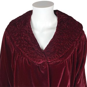 May include: A burgundy velvet robe with a quilted collar. The robe has a button closure and long sleeves.