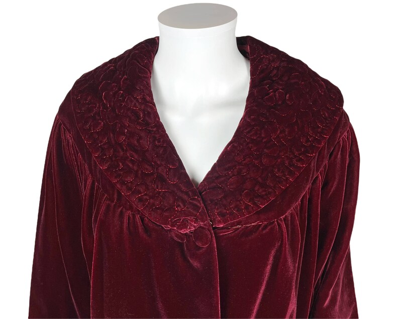 May include: A burgundy velvet robe with a quilted collar. The robe has a button closure and long sleeves.