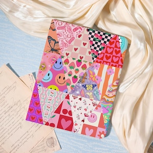 May include: A colorful patchwork design featuring various patterns, including smiley faces, strawberries, butterflies, hearts, and cherries. The design is predominantly pink, red, and orange, with a mix of other colors. The item is likely a case or cover for a tablet or similar device.