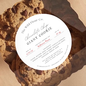 May include: A brown cardboard box with a clear window displaying giant chocolate chip cookies. The box has a circular label that reads "Chocolate Chip Giant Cookie" with ingredient details. The text "Perfect as cookie labels" is also visible.