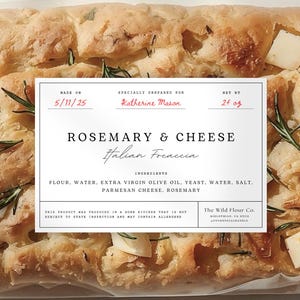 以下が含まれることがあります： ローズマリーとチーズのフォカッチャの包装されたパン。ラベルには「Rosemary & Cheese Italian Focaccia」と材料が記載されています。パンは、ローズマリーの小枝とチーズの立方体が入った、黄金色です。