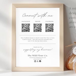 May include: A framed print with the text "Connect with me" and social media QR codes. The Wild Flour Co. logo is at the bottom. Three loaves of sourdough bread are in clear bags with tags that read "Sourdough Bread".