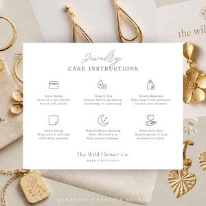 May include: A white jewelry care instruction card featuring black text and icons, surrounded by gold-toned earrings and a necklace. The card includes sections for storing, keeping dry, avoiding chemicals, cleaning, and wearing with care.