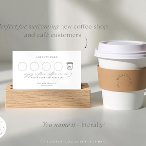 K&ouml;nnte beinhalten: Ein wei&szlig;er Pappbecher mit brauner H&uuml;lle und wei&szlig;em Deckel, neben einem Holzkartenhalter mit einer Kundenkarte. Die Karte hat Kreise f&uuml;r Stempel und den Text "Genie&szlig;en Sie einen kostenlosen Kaffee".