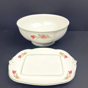May include: White ceramic serving bowl and rectangular platter with floral and lattice designs. The bowl has a pedestal base and the platter has scalloped edges. Both pieces have green trim and floral accents.