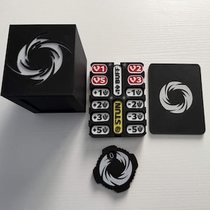 May include: A black box, game cards, and tokens with a white spiral design. The tokens have numbers and the word "STUN" in yellow. The cards and box also feature the spiral design. The game pieces are on a white surface.