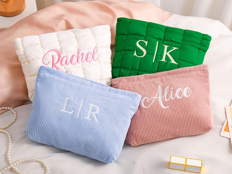 Peut inclure: Quatre trousses de maquillage personnalis&eacute;es de couleurs vari&eacute;es : blanc, vert, bleu et rose. Le sac blanc est matelass&eacute; et brod&eacute; avec "Rachel". Le sac vert porte "S|K". Le sac bleu porte "L|R". Le sac rose porte "Alice".
