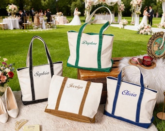 May include: Four canvas tote bags with names embroidered on them. The bags are white with colored trim in black, green, brown, and blue. The bags are on a white fluffy surface with a wedding scene in the background.