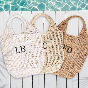 Puede incluir: Tres bolsas de mano de crochet blancas y marrones con iniciales bordadas en negro LB, C y FD.