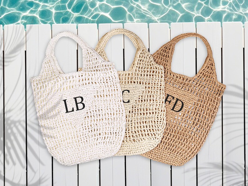 Puede incluir: Tres bolsas de mano de crochet blancas y marrones con iniciales bordadas en negro LB, C y FD.