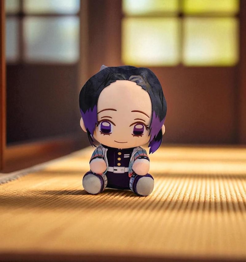 Op de afbeelding: Een pluche pop van een anime-personage met zwart haar en paarse highlights. De pop draagt een zwart-witte outfit met een paars-wit jack met patroon. De pop zit op een lichtbruin oppervlak.