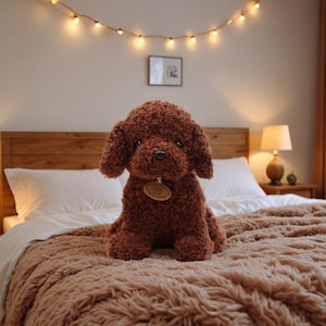 May include: A plush brown dog toy with curly fur sits on a bed with a brown blanket. The dog has a small tag around its neck. A string of lights hangs above the bed, and a lamp sits on a nightstand.