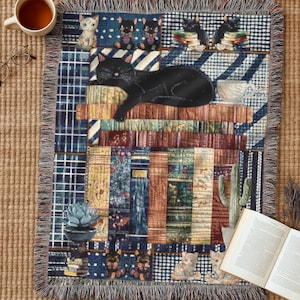 Puede incluir: Una manta tejida con un collage de gatos negros, libros apilados y suculentas en macetas. El diseño incluye un gato negro grande descansando sobre una pila de libros, rodeado de varios patrones, tonos azules y marrones y bordes con flecos.