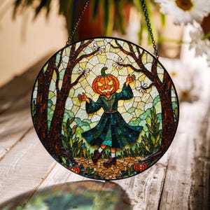May include: Round stained glass panel featuring a figure with a jack-o'-lantern head in a green dress, set in a forest scene. The artwork includes trees, foliage, and small pumpkins, with a chain for hanging. The color palette includes orange, green, and brown.