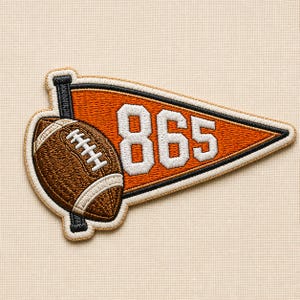 May include: An embroidered patch featuring a triangular orange pennant with a black border and the white number 865. A brown American football with white laces is positioned on the left side, attached to a black vertical pole element.