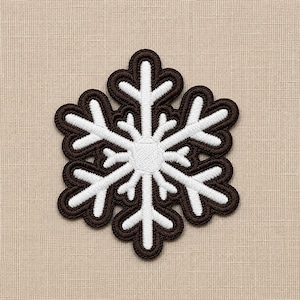 May include: A snowflake-shaped embroidered patch featuring a dark brown outer border and a white inner design. The patch has a six-pointed star structure with intricate branching arms and a circular center, all rendered in dense thread stitching.