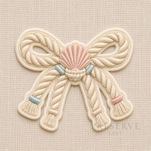 May include: Embroidered nautical bow with a seashell centre. The bow is made of cream-coloured rope-like material, with a pink and blue seashell accent. The bow's tails have tassels. The background is a light beige fabric.