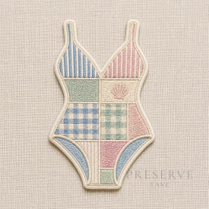 May include: Embroidered swimsuit-shaped patch. The design is a patchwork of blue, pink, and green sections, with stripes, gingham, and a seashell motif. The patch is outlined in cream.