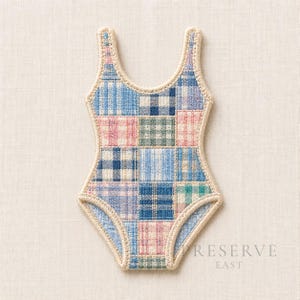 Puede incluir: Un bañador de estilo patchwork en tonos azules, rosas y verdes, con ribete color crema. El diseño de una pieza presenta un escote redondo y una pernera de corte alto. El texto "RESERVE EAST" es visible en la esquina inferior derecha.