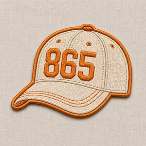 May include: An embroidered patch shaped like a baseball cap in beige with a thick orange border. The cap features the number 865 stitched in bold orange thread across the front panels, with orange stitching details defining the cap structure.