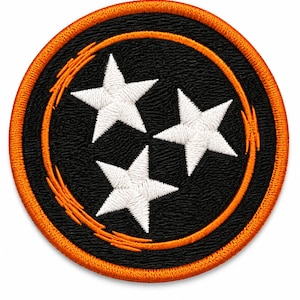 Op de afbeelding: Een ronde geborduurde patch met een zwarte achtergrond en drie witte sterren in een driehoekige opstelling. De patch is omrand met een dikke oranje gestikte rand en bevat een oranje cirkelvormige accentlijn rondom de sterren.