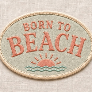 May include: An oval-shaped embroidered patch featuring a sage green background with a cream-colored border. The text BORN TO BEACH is stitched in coral-colored thread above a stylized coral sun rising over two wavy teal lines.