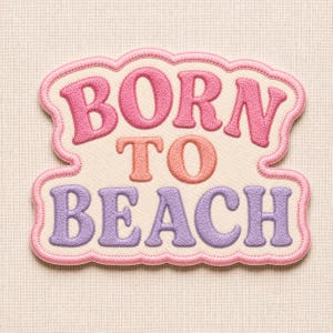 Op de afbeelding: Een stoffen embleem met een geschulpte rand en de geborduurde tekst BORN TO BEACH. Het woord BORN is roze, TO is koraalkleurig en BEACH is lavendelkleurig, alles op een crèmekleurige achtergrond met een roze gestikte omlijning.
